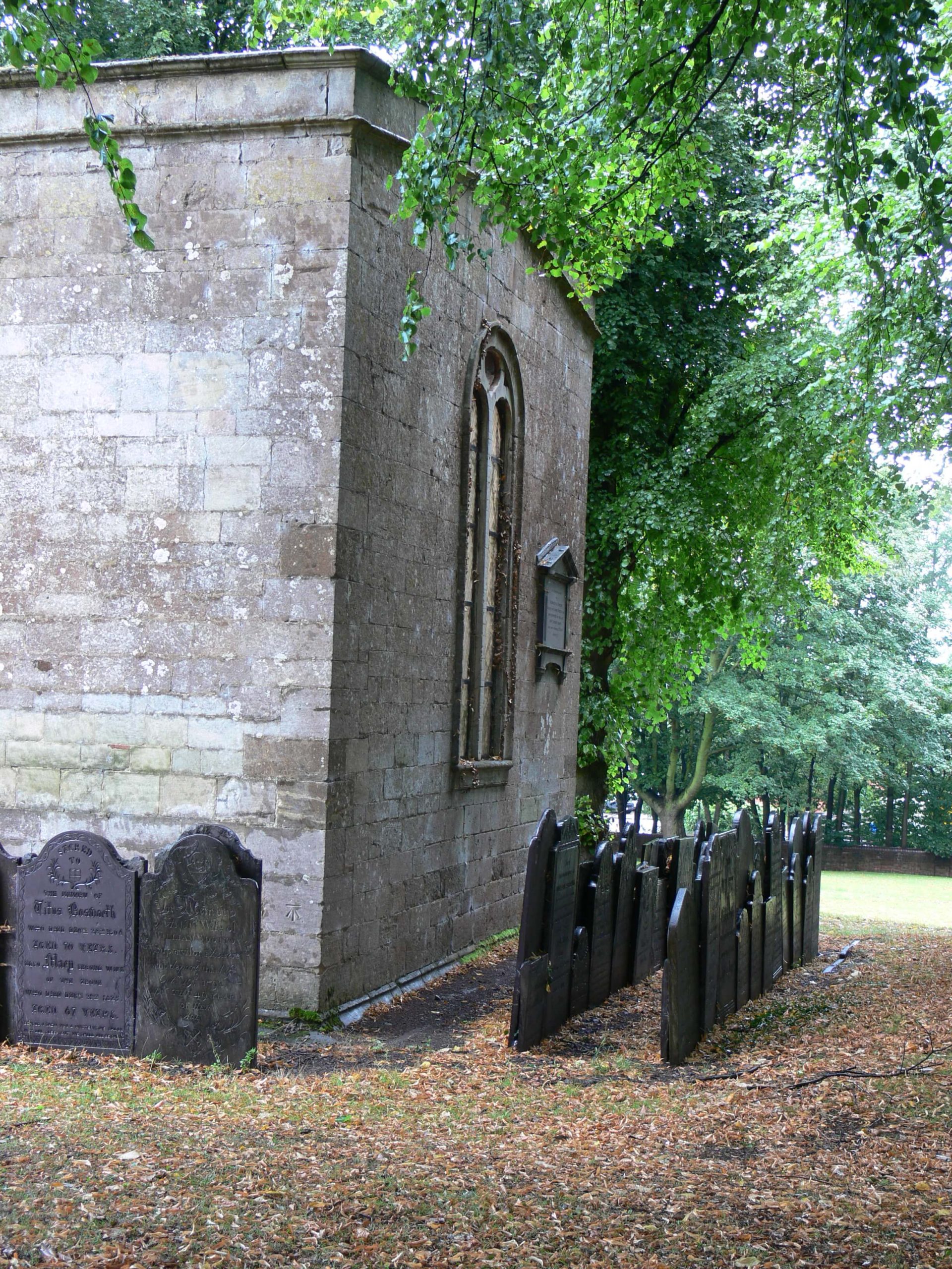 Row of slate headstones and church, St Mary in Arden, Market Harborough.