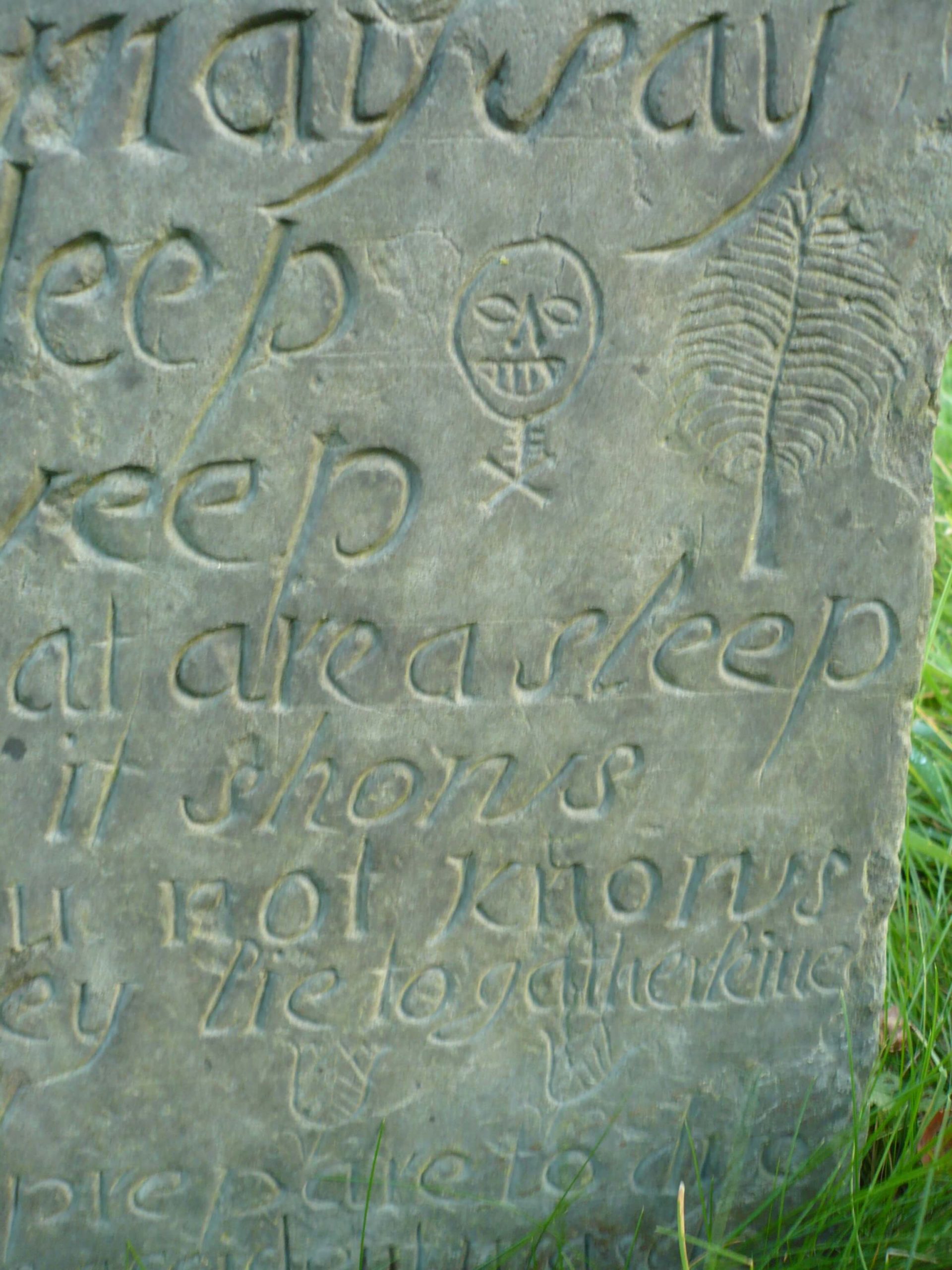Swithland slate headstone in Burton Overy Churchyard, Leicestershire showing a skull and crossbones and leaf.