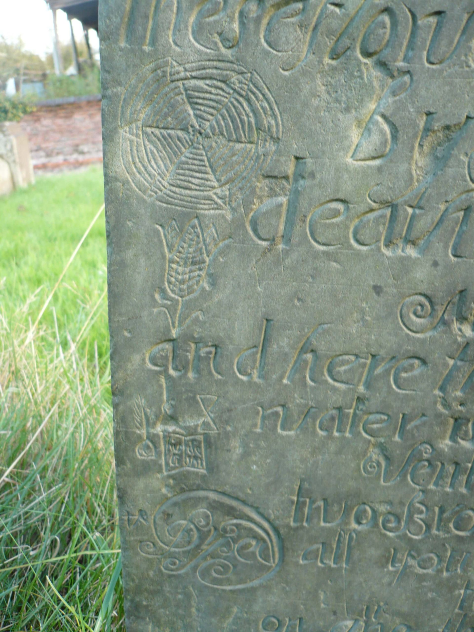Swithland Slate Headstone in Burton Overy churchyard, Leicestershire showing carvings of a cobweb, tulip and hourglass.
